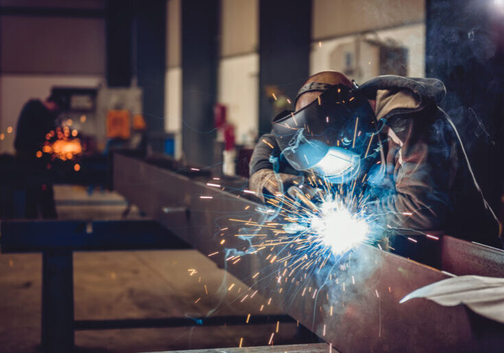 Industrial Welder With Torch Industrial Welder With Torch and Protective Helmet in big hall welding metal profiles